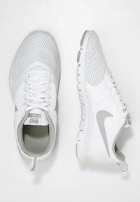 Hvide Nike løbesko med grå swoosh, mesh-overdel og snørebånd; den ene sko set fra oven, den anden fra siden.