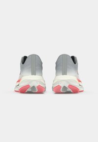Scarpe da corsa con tomaia grigia, intersuola bianca e dettagli rosa; presentano una suola testurizzata e un design senza cuciture.