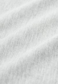 Tissu en coton blanc avec une texture douce et lisse. Des variations subtiles de teinte créent un aspect léger et chiné.