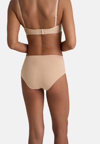 Beige beha en hooggeplaatste slip set van gladde stof, met verstelbare banden en een haak-en-oogsluiting aan de achterkant.