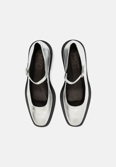 Hõbedased metallik Mary Jane kingad ümarate nelinurksete varvastega, musta tallaga ning pahkluude ümber kinnitaud hõbedase pandlaga. Sile pealistekstuur.