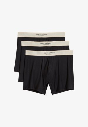 Drei schwarze Herrenboxershorts mit beigen elastischen Taillenbändern mit der Aufschrift "Marc O'Polo EST. IN STOCKHOLM" auf einem weißen Hintergrund gestapelt.