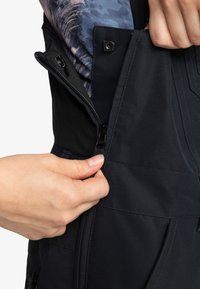Zwarte buitenjas met rits en een zachte binnenvoering. Handmatige aanpassing van de rits in de taille. Heeft een gestroomlijnd ontwerp met gestikte accenten.