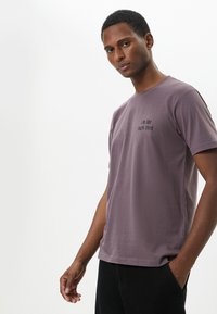 Herr T-shirt med kort ärm i mjuk lavendelfärg, med ett tryck framtill som säger "jag är typ 104% trött." Klassisk rundhals och avslappnad passform.