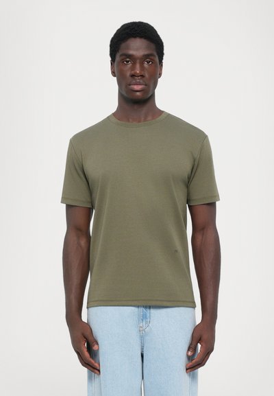 Olijfgroen t-shirt met korte mouwen, gemaakt van zachte katoen, met een klassieke ronde hals en een ontspannen pasvorm. Subtiele logo aan de zoom.