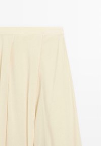 Plissé rok van zacht beige stof met een gladde textuur en een rechte tailleband. Bevat subtiele stiksels langs de bovenkant.