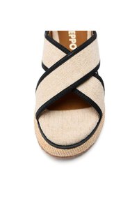 Sandalia de lienzo beige con acentos negros, que presenta tiras entrecruzadas, un diseño de dedo al aire y una suela texturizada para agarre y comodidad.