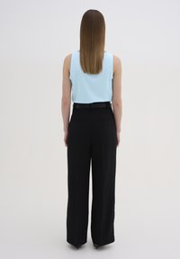Un top bleu deschis cu rigle, fără mâneci, purtat împreună cu pantaloni largi negri, cu talie înaltă. Ansamblul include o curea neagră și are un finisaj neted.