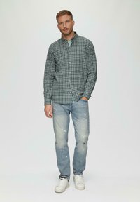Groen en marineblauw geruit overhemd, lange mouwen, knopen aan de voorkant, gecombineerd met lichtblauwe versleten jeans en witte sneakers. Eenvoudig ontwerp, casual pasvorm.