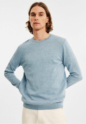 Lyst bluse lavet af blødt, tekstureret stof. Har en rund halsudskæring og ribstrikkede manchetter og kant. Tætsiddende silhuet.
