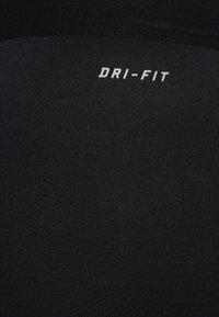 Schwarzer Dri-FIT-Stoff mit glatter Textur. Mit einem sichtbaren weißen "DRI-FIT"-Logo in der Nähe der oberen Kante. Entwickelt für das Feuchtigkeitsmanagement.