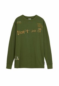 T-shirt a maniche lunghe verde oliva, con testo e grafiche arancioni, tra cui "NON FARLO" e un piccolo design in basso a sinistra.