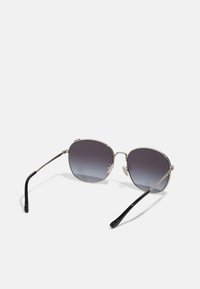Óculos de sol metálicos com uma armação prateada, lentes quadradas que fazem um degradé de cinza escuro para cinza mais claro, e hastes pretas.