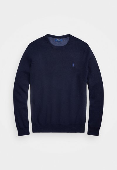 Navy modra pletena majica z okroglim izrezom, dolgimi rokavi in majhnim vezenim logotipom na levi strani prsnega koša. Gladka tekstura.