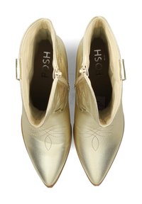 Gold ankle boots feature a pointed toe, textured faux leather exterior, and subtle floral stitching on the front. Zipper closure on sides.