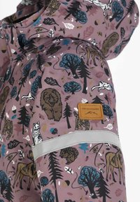 Mouw van een paarse kinderjas met prints van bosdieren, een reflecterende strip en een bruine Swedemount logo patch.