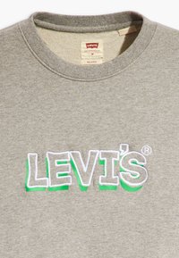 Siva majica dugih rukava s okruglim izrezom, s izvezenim "LEVI'S" logom u bijeloj i zelenoj boji. Mekana tekstura, ležerni kroj, srednja veličina.