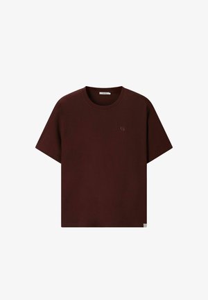 Donkerbruine T-shirt met korte mouwen en ronde hals, met een klein subtiel logo op de linkerborst en een klein labeltje aan de onderzoom.