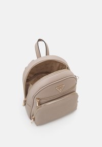 Sac à dos en simili cuir beige avec quincaillerie dorée, compartiments à double fermeture éclair et une poignée supérieure. L'intérieur présente une doublure marquée.