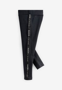 Melnas legingi no elastīga auduma ar sānu svītru un uzrakstu "BAKER by TED BAKER." Pielāgota piegrieztne ar gludu tekstūru.