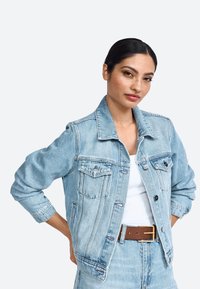 Giacca in denim azzurro chiaro con colletto classico, tasche frontali e accessori in argento. Presenta una vestibilità rilassata e un tessuto testurizzato.