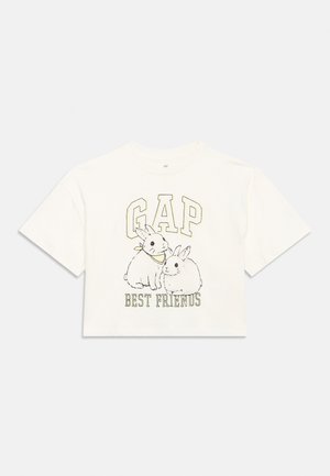 Camiseta blanca recortada con dos conejos ilustrados, "GAP" en letras grandes arriba y el texto "Mejores Amigos" debajo de los animales.