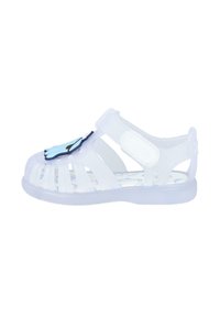 Sandal de gel transparente con diseño recortado, correa ajustable y acento en forma de mano azul en la puntera. Presenta una plantilla con patrón.