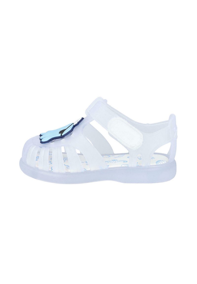 Sandal de gel transparente con diseño recortado, correa ajustable y acento en forma de mano azul en la puntera. Presenta una plantilla con patrón.