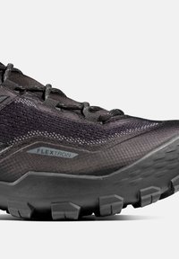 Schwarzer Sportschuh mit strukturiertem Obermaterial, auffälligem Schnürsystem und robustem Sohle mit markanten Profilmustern. Seitliches Logo sichtbar.