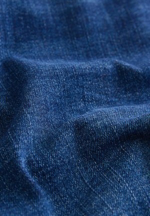 Denimstof i dyb blå med en blød tekstur, der har subtile farvevariationer og et standard vævemønster. Ingen synlige metaller eller accenter.