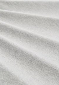 Tessuto grigio chiaro con una superficie liscia, che mostra leggere variazioni e pieghe, indicanti morbidezza e caduta. Senza motivi o dettagli notevoli.