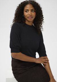 Black, ribbed knit sweater with short puffed sleeves, paired with a dark brown suede skirt. Simple, fitted design with crew neckline.