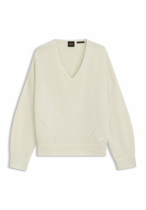 Krämfärgad stickad tröja med V-hals, nedfallna axlar och ribbade muddarna. Har dekorativ sömnad och en avslappnad silhuett.