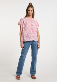 Top in tessuto leggero con motivo paisley rosa, maniche corte, vestibilità comoda, abbinato a jeans azzurri e sandali marroni.