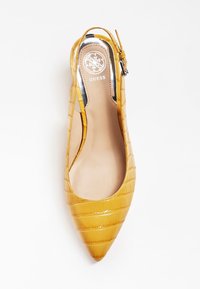 Escarpins plats en cuir verni jaune, avec un bout pointu et une texture crocodile. Dotés d'un logo en argent et d'une bride de cheville réglable.
