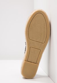 Espadrillesula, gjord av beige gummi, har ett strukturerat mönster. Kanten är insvept i jute, vilket ger ett naturligt utseende och bra grepp.