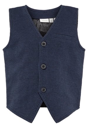 Chaleco azul marino texturizado con escote en V, tres botones negros y un pequeño bolsillo. Presenta un forro liso y un dobladillo afilado y angular.