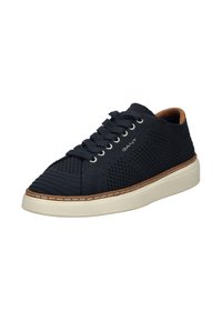 Granatowe sneakersy z teksturowanej siateczki, okrągłym noskiem, białą podeszwą i brązowymi skórzanymi akcentami. Posiada sześć otworów na sznurówki i płaskie sznurówki.