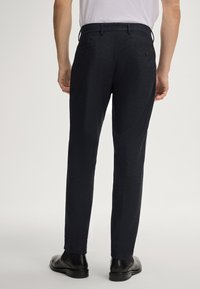 Marineblauwe broek met een geweven textuur, slim fit en twee achterzakken. Voorzien van bijpassende riemlusjes en zwarte gepolijste schoenen.