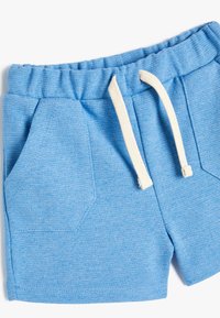 Pantalones cortos de algodón azules con cintura elástica, cordón blanco, dos bolsillos laterales en ángulo y tejido texturizado.