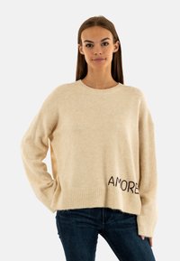 Maglione lavorato a maglia beige con orlo a coste, maniche larghe e la scritta "AMORE" ricamata in filo scuro sul davanti. Tessuto morbido e vestibilità comoda.