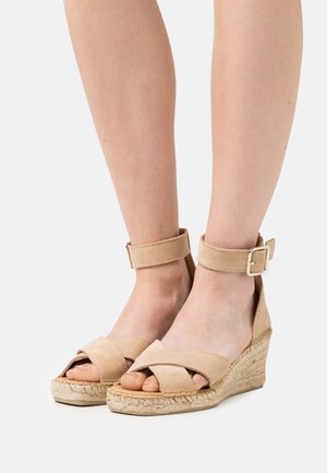 Beige espadrille wedge sandalen met een kruis-bandontwerp, enkelschoenen en een jute-wrapped hak. Zacht suède textuur en open neus stijl.