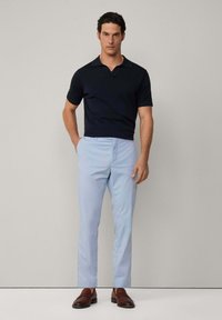 Marinblå kortärmad polo, ljusblå byxor, bruna läderloafer. Slät tyg, skräddarsydd passform, minimalistisk design, inga synliga mönster.