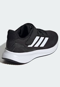 Scarpa sportiva nera con tomaia in rete testurizzata, tre strisce bianche e colletto imbottito. Presenta una fascia nera e una suola spessa bianca.