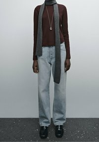 Burgundy long-sleeve top, gray scarf, light blue wide-leg jeans, and black shoes. Smooth fabric textures; scarf and top have a fitted design.