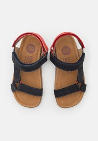 Marine- og røde lædersandaler med velcro-stropper og en brun fodseng; har kontraststing og en polstret indersål for komfort.