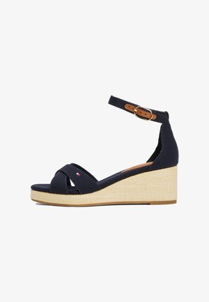 Sandale wedge din pânză bleumarin, cu curele încrucișate, curea ajustabilă pentru gleznă și o platformă țesută natural. Accent cu logo distinctiv.