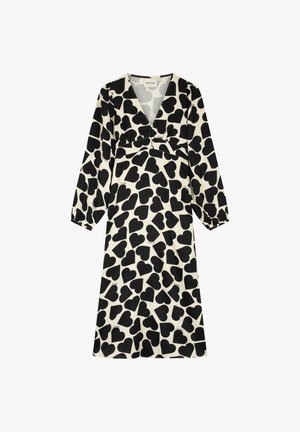 Zwarte hartpatronen op een crèmekleurige achtergrond, lange mouwen, een diepe V-hals en plooien bij de buste creëren een vloeiende, ontspannen silhouet.