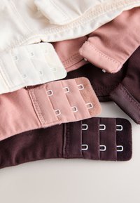Crochets et agrafes de soutien-gorge en beige, rose poudré et brun foncé, montrant les détails de la fermeture réglable sur des bandes de tissu doux.