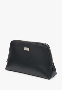 Černá kožená taštička obdélníkového tvaru, se stříbrným zipem a malou kovovou logovou destičkou na přední straně. Hladký povrch.